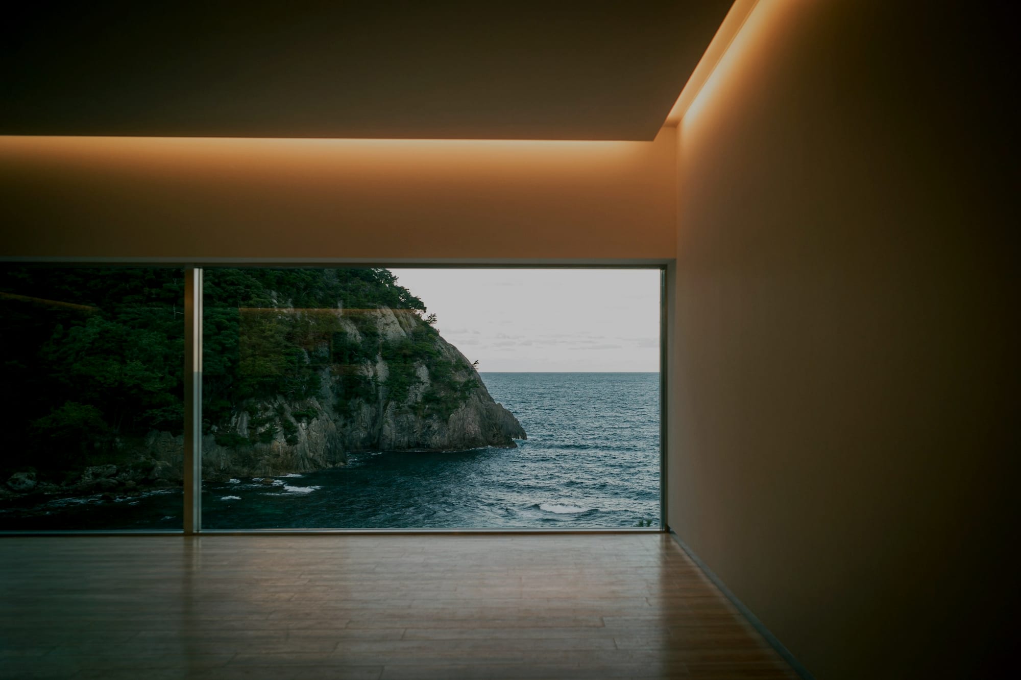 The principal volume, empty, opening the full width of the west wall to the water.